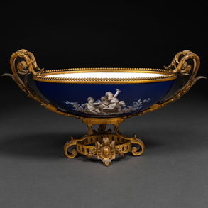 Centerpiece in enameled porcelain with putti decoration on both sides and gilded bronze frame of the nineteenth century.