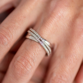 Intertwined ring with a double border of diamonds in 18kt white gold.