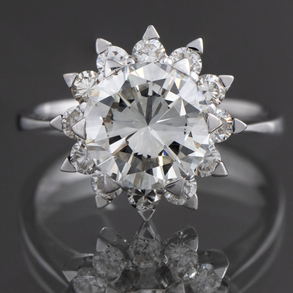 Solitaire ring with a central brilliant bordered with diamonds in 18 kt white gold.
