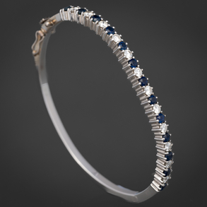 Rigid bracelet in 18kt white gold with a front bordered with diamonds and sapphires.