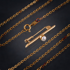 Conjunto de cadena e imperdible con perlita en oro amarillo de 18 kt.