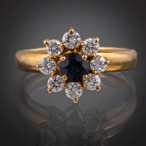 Anillo en oro amarillo de 18 kt con zafiro central y orlado de brillantes.